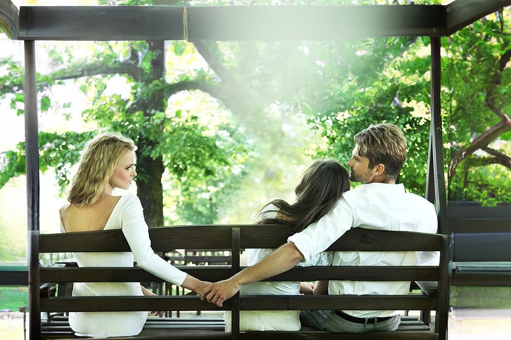um casal de marido e mulher e uma mulher sentados em um jardim
